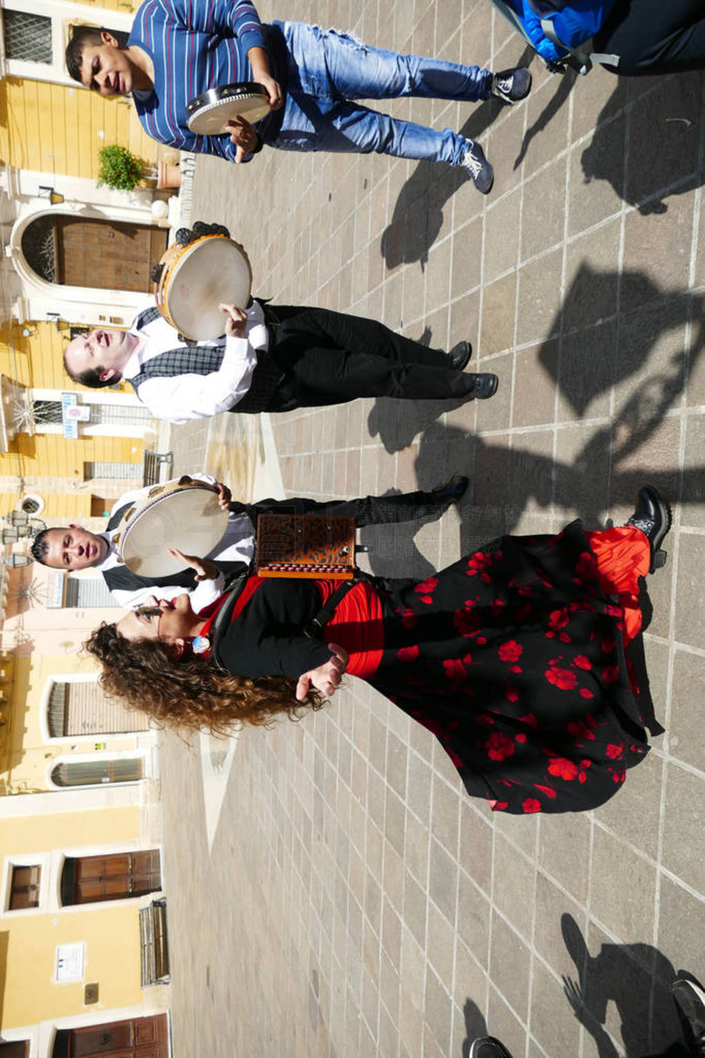Woman in red and men on tambourines playing pizzica music