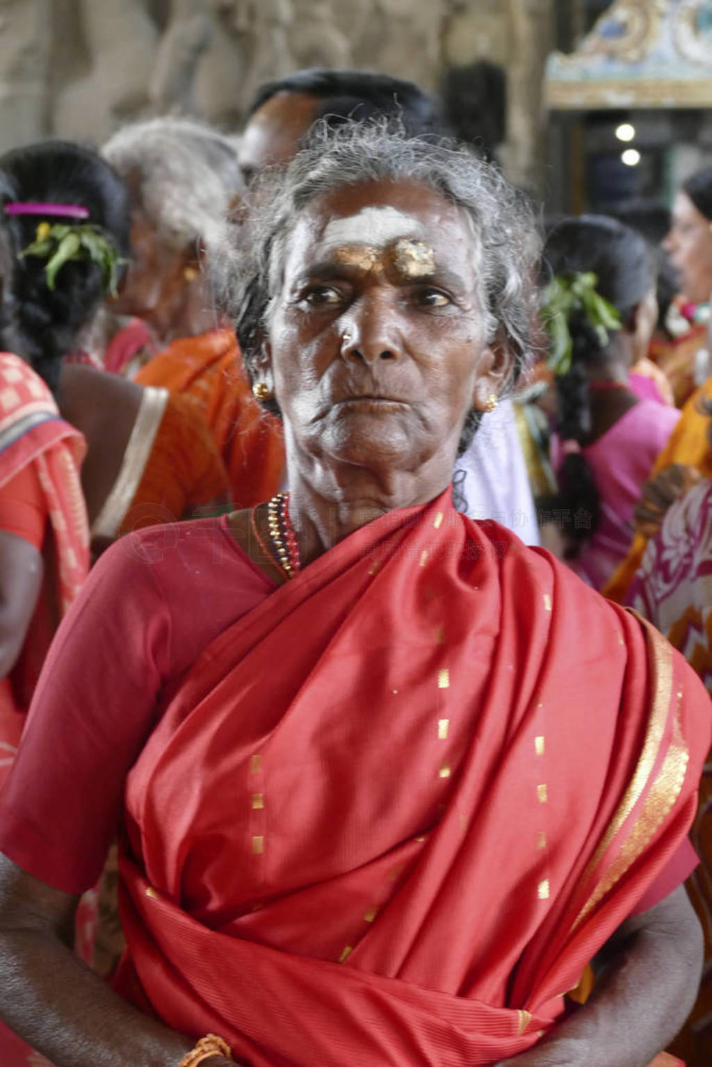 Women pilgrims wear red sarees in the Maha Mandapa
