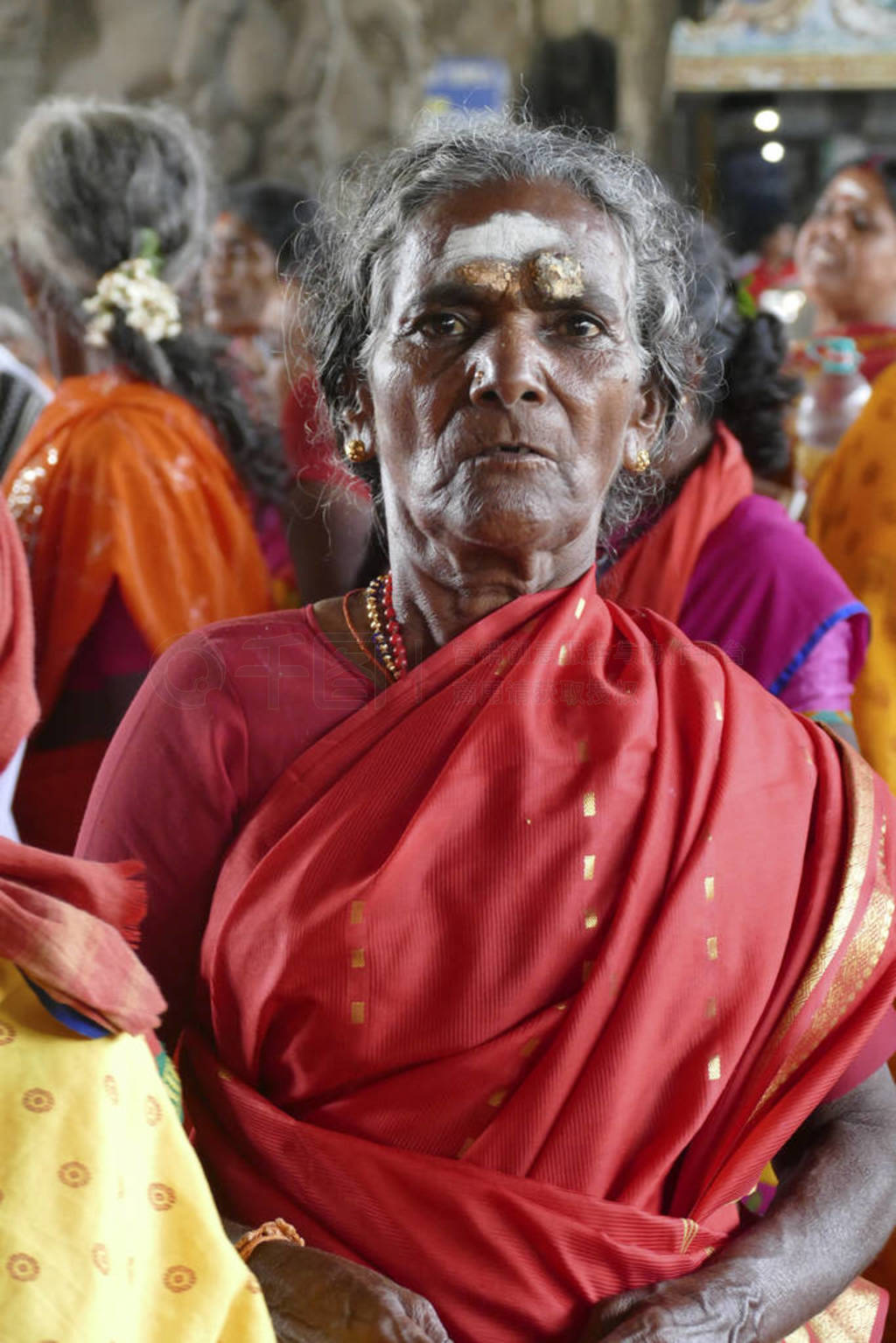 Women pilgrims wear red sarees in the Maha Mandapa