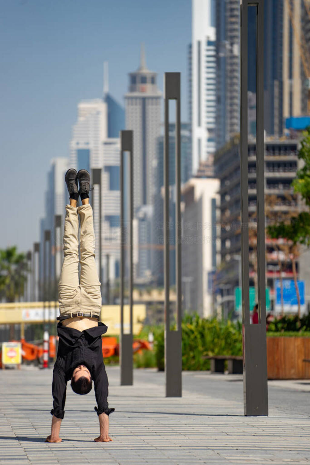 Acrobat keep balance one the hands with blurred Dubai cityscape.