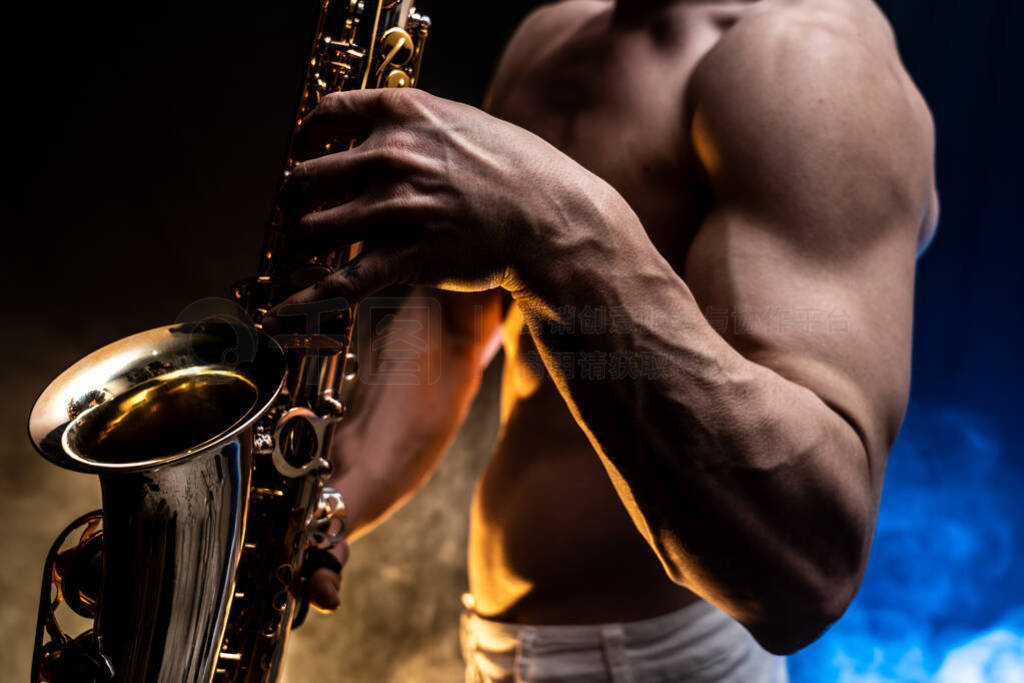 Muscular man with naked torso playing on saxophone with smoked c