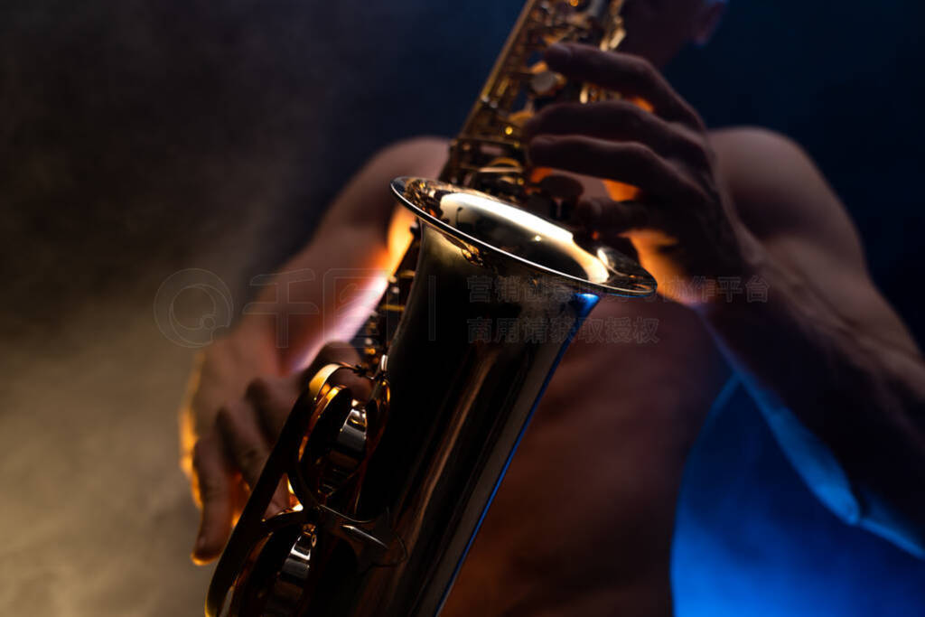 Muscular man with naked torso playing on saxophone with smoked c