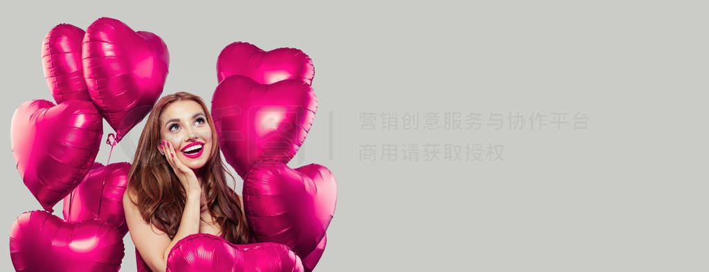 Young model woman having fun and holding pink heart balloons