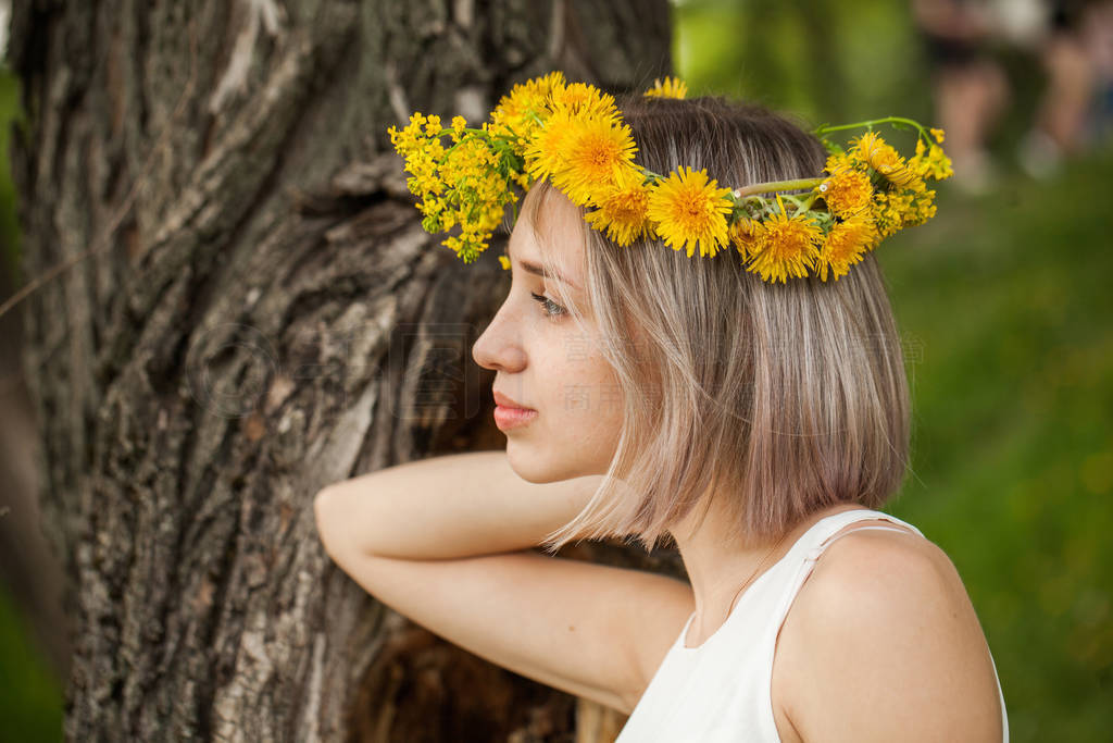 Young pretty woman in yellow flowers wreath outdoor.