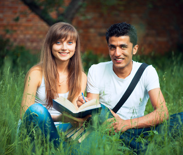两个学生男生和女生在公园草地与书上学习