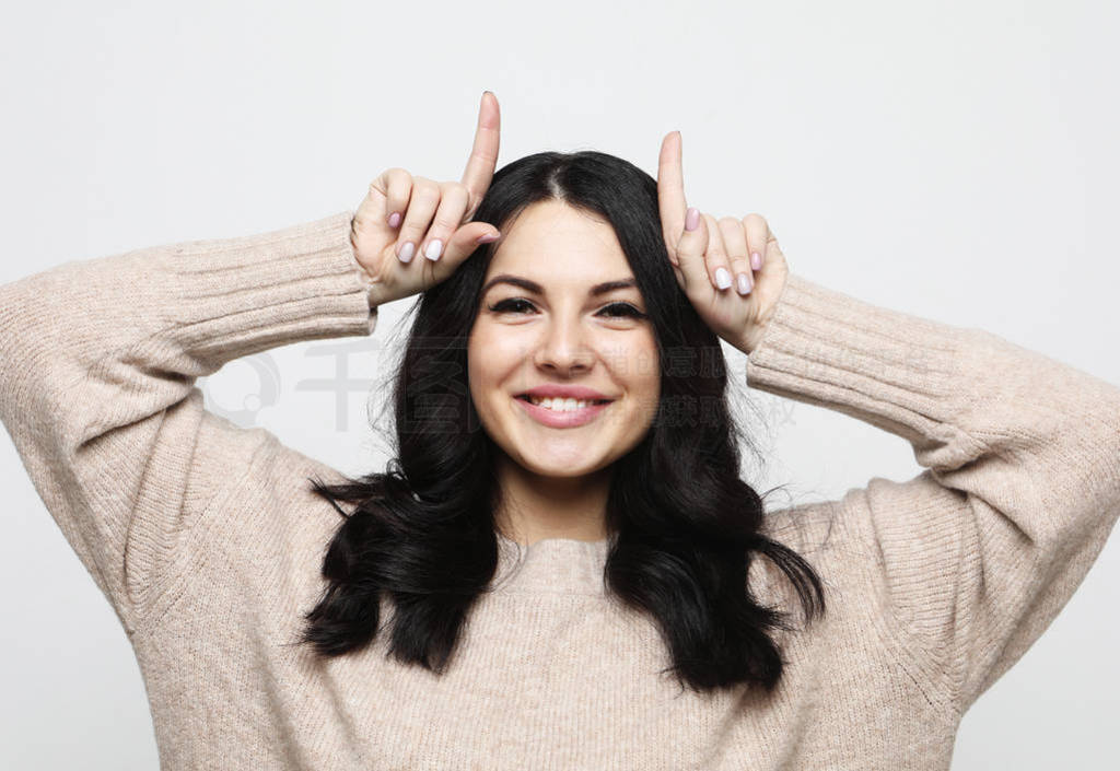 smiling girl with raised hands holding fingers as antlers on h