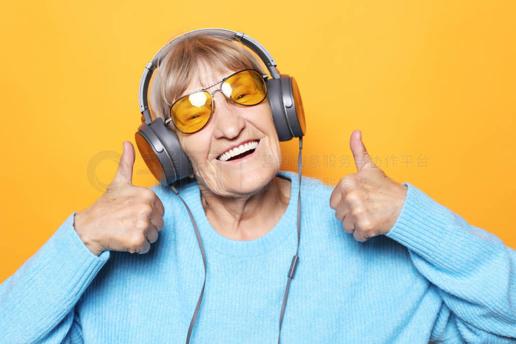 Funny old lady listening music and showing thumbs up.