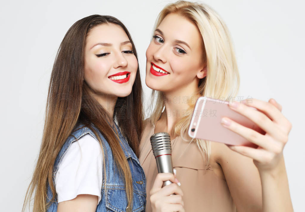 two beauty girls with a microphone take selfie with smartphone