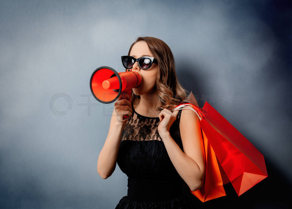 Style woman in sunglasses with shopping bags and louder on grey