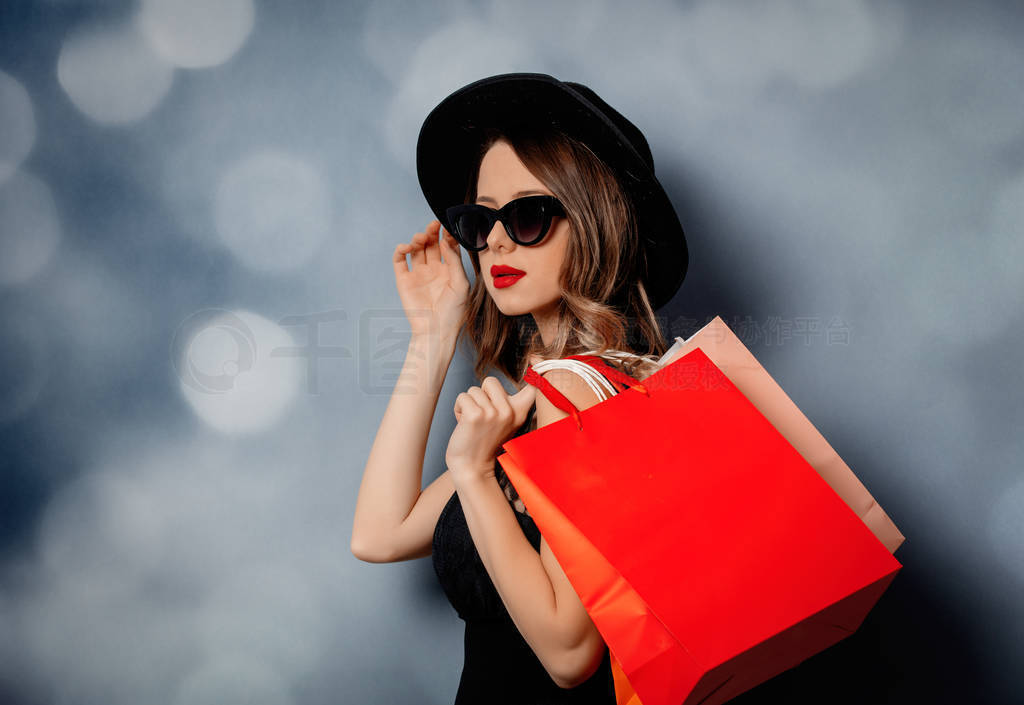 Style woman in sunglasses with shopping bags on grey background