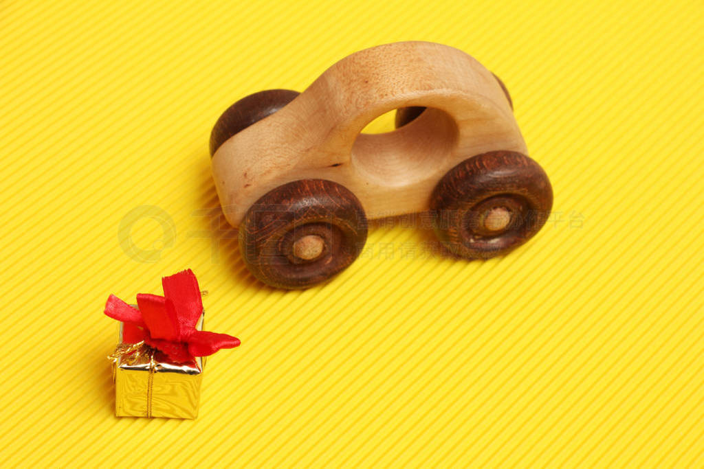 wooden car toy and golden gift box with red ribbon on corrugated