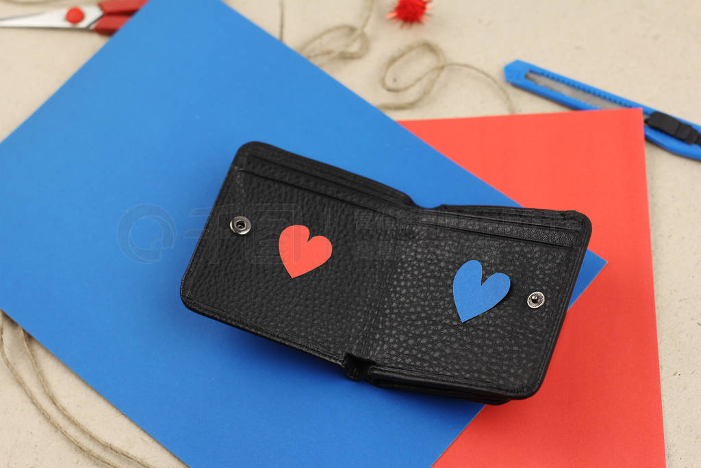 black leather wallet with two paper hearts red and blue on craft