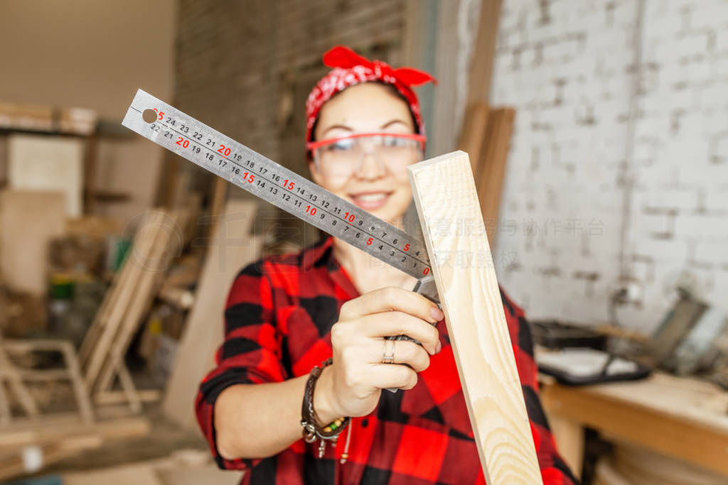 Woman professional works with wood and measures it with a ruler