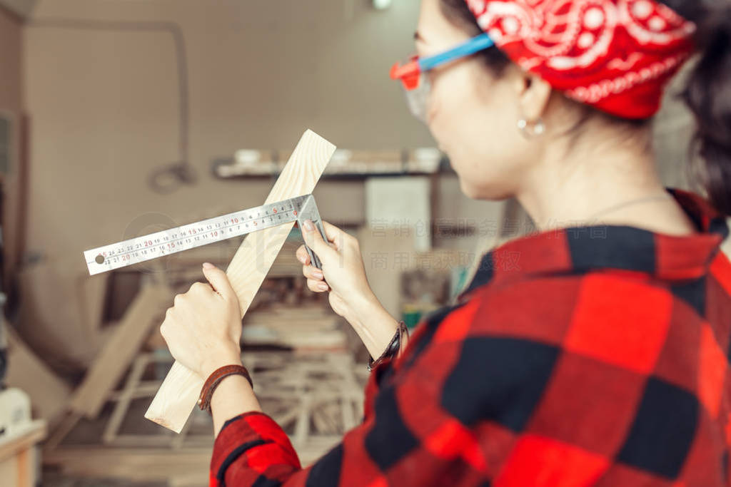 Woman professional works with wood and measures it with a ruler