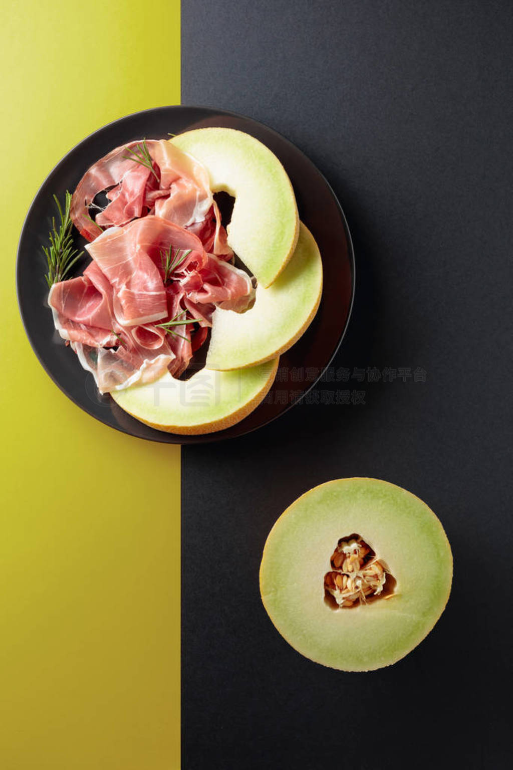 Prosciutto with rosemary and melon on a black plate.