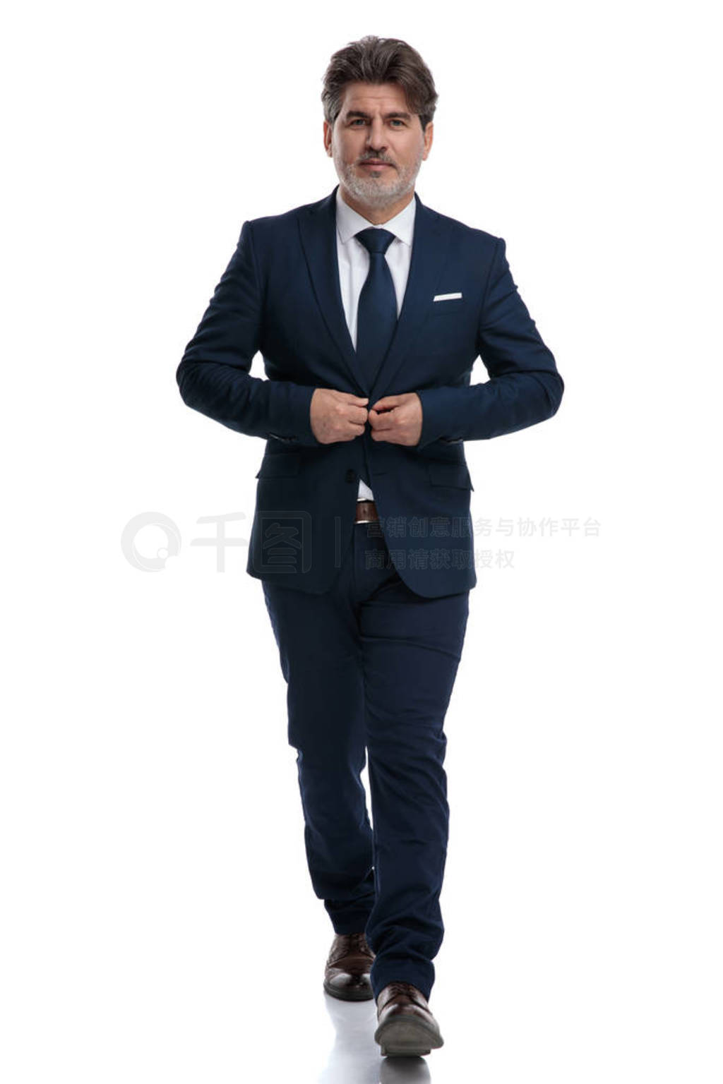 Elegant businessman walking forward and fixing his jacket