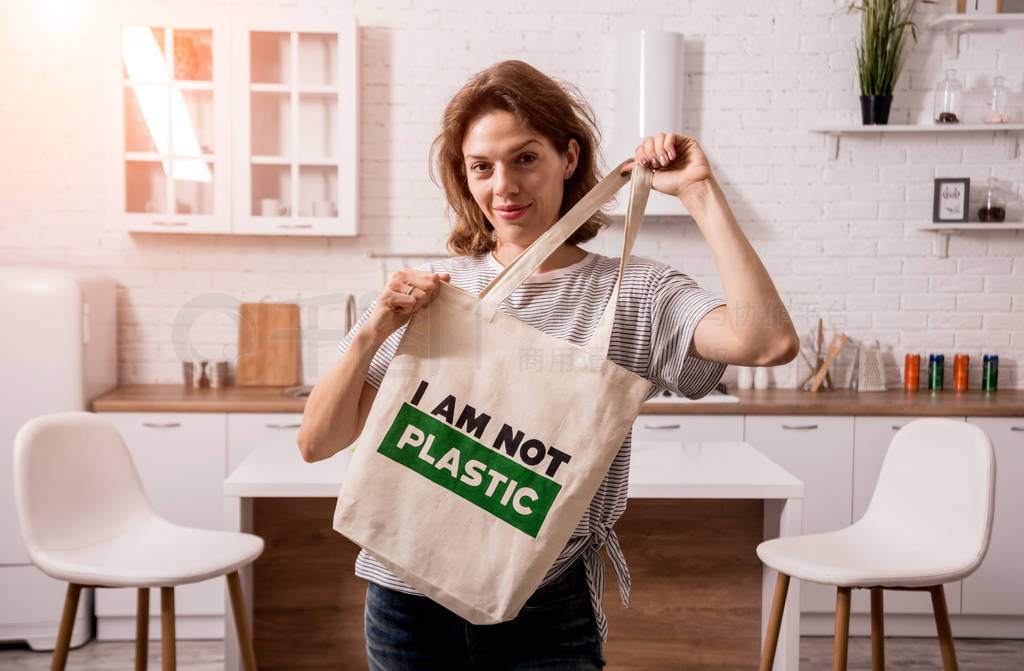 Young girl holding a cloth bag. At the kitchen. I am not plastic