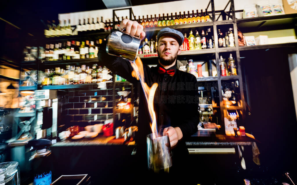 The bartender makes a cocktail with a fire show at the bar.