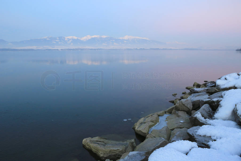 stones under snow on mountain lake shore
