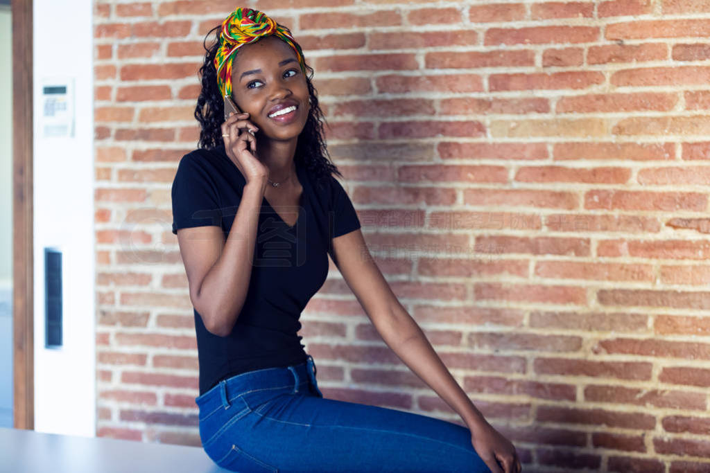 Happy young woman talking on mobile phone while sitting on a tab