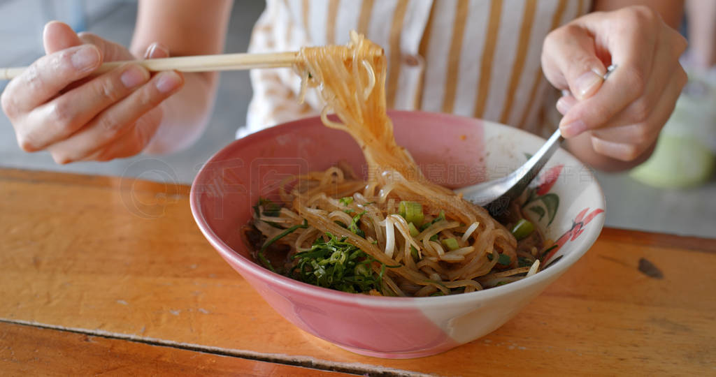 Woman eat boat noodles at outdoor street vendor in Thailand