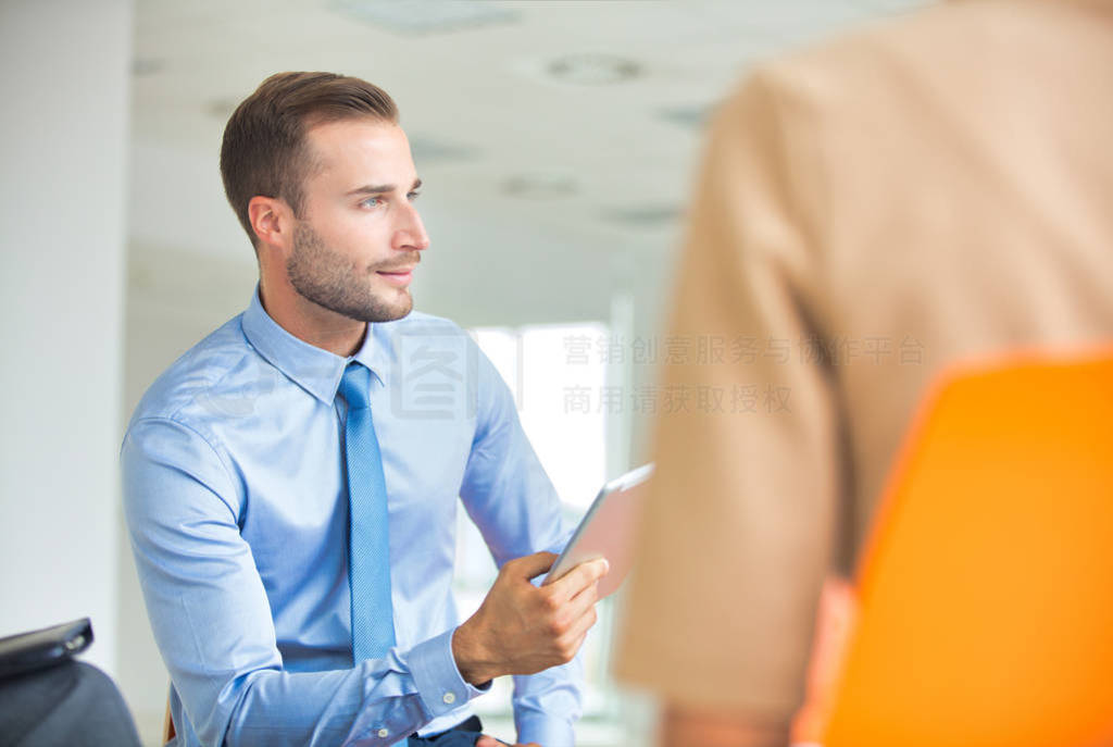 Smiling young businessman sitting with colleague during meeting