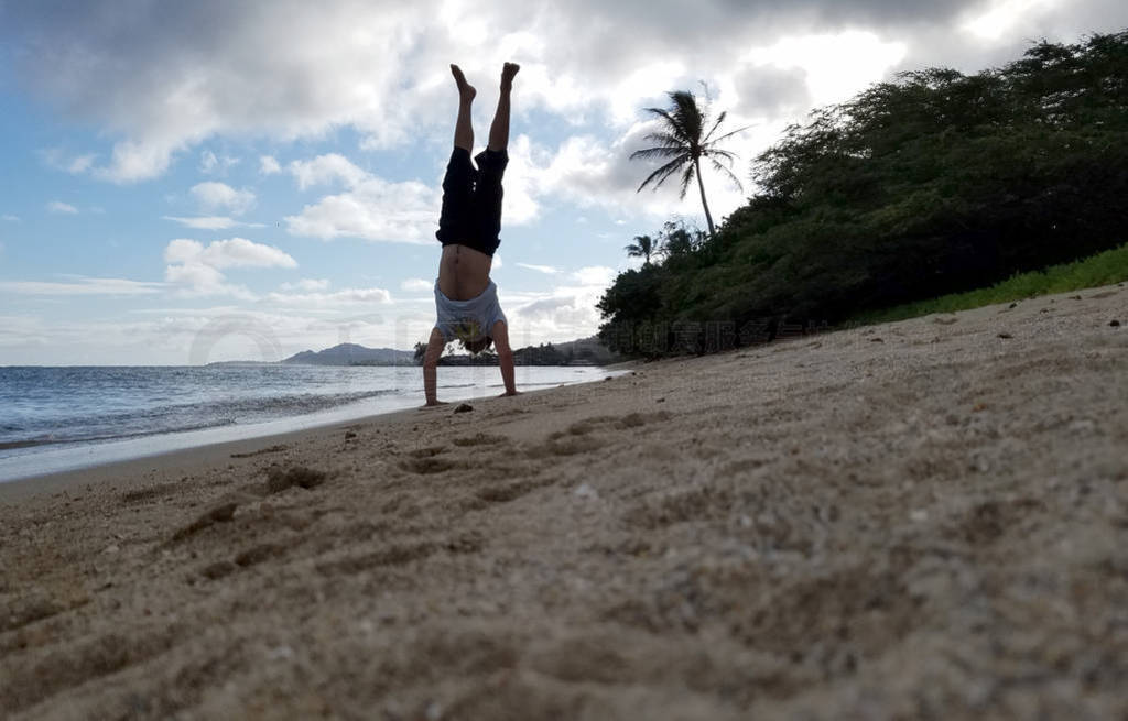 Man Handstand on beach as wave roll on to shore