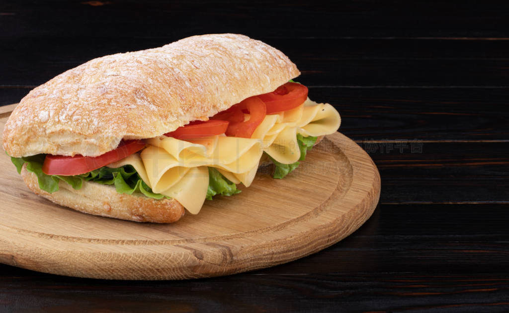 Ciabatta sandwich with lettuce and cheese on wooden board with