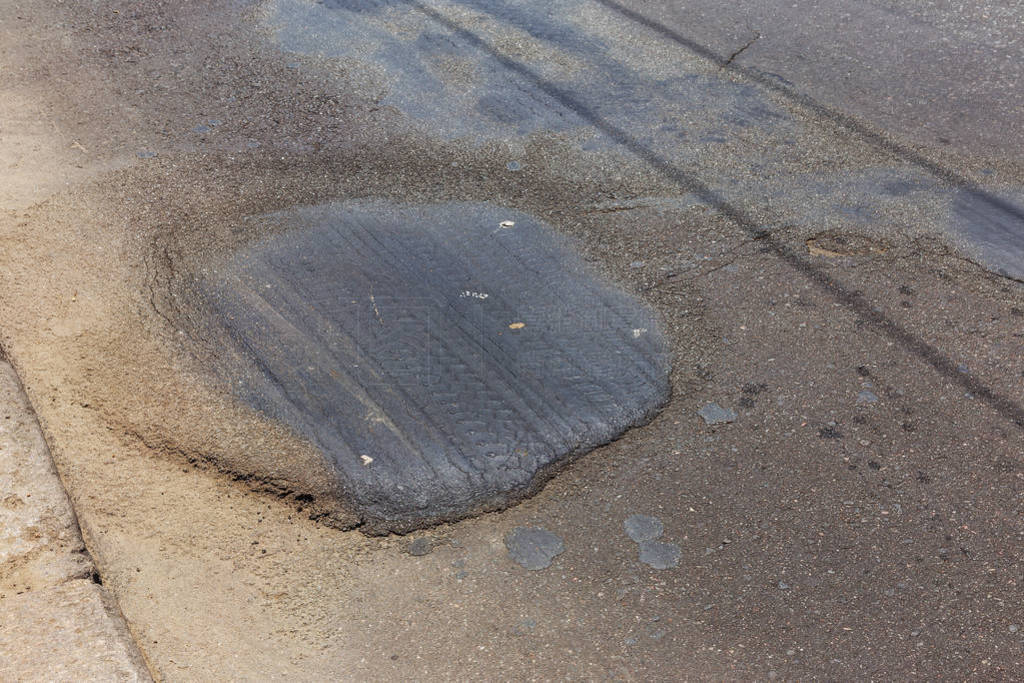 Damaged road, asphalt cracks. Asphalt with potholes and asphalt