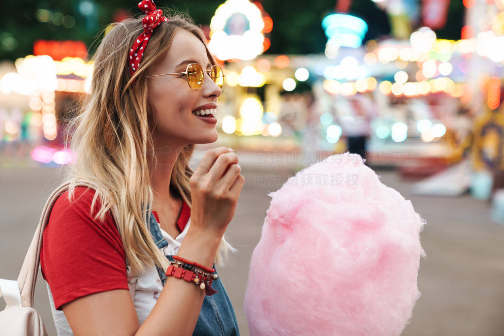 Image of blonde beautiful woman eating sweet cotton candy while