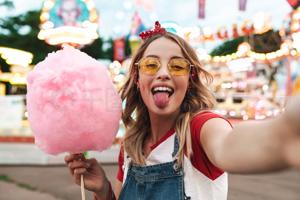 Image of positive blonde woman holding sweet cotton candy while