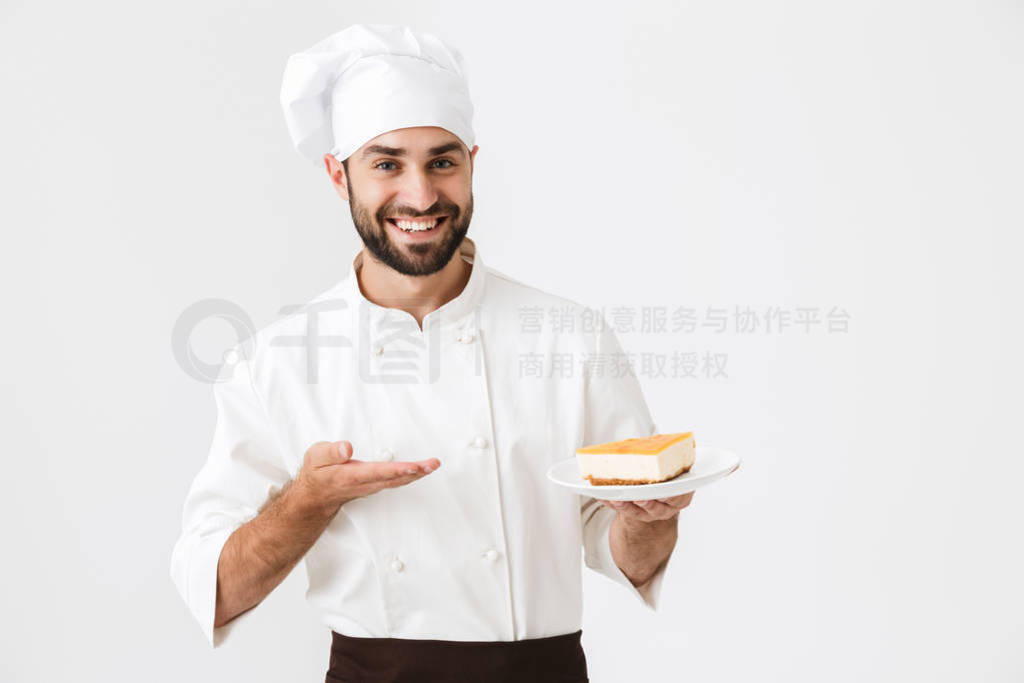 Image of handsome chief man in cook uniform smiling and holding