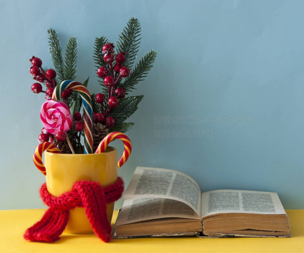 Christmas candy canes in yellow mug with berries holly branches