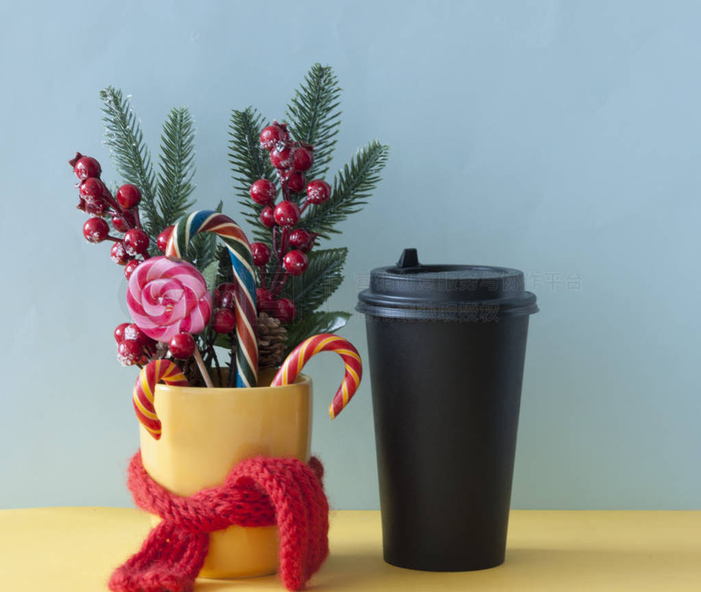 Christmas candy canes in yellow mug with berries holly branches