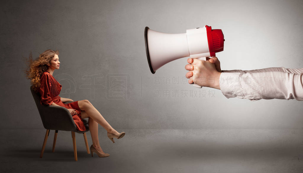 Elegant model sitting opposite with a big loudspeaker