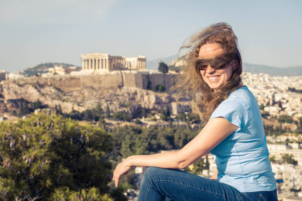 Young pretty woman sits at hilltop in Athens, Greece. Beautiful