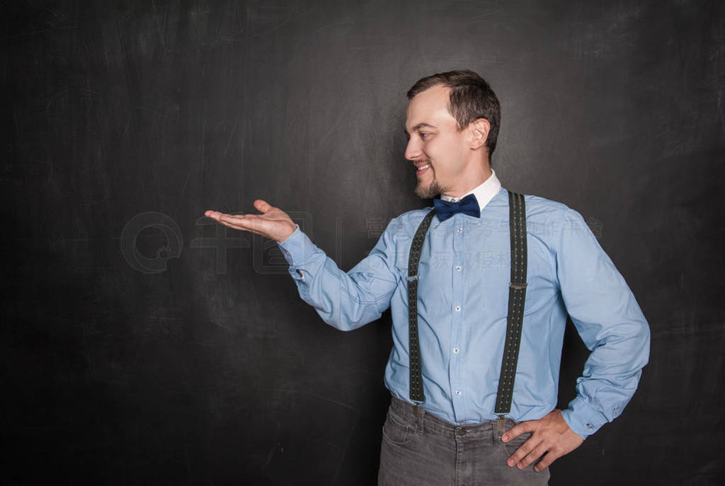 Handsome man showing something on his hand on blackboard