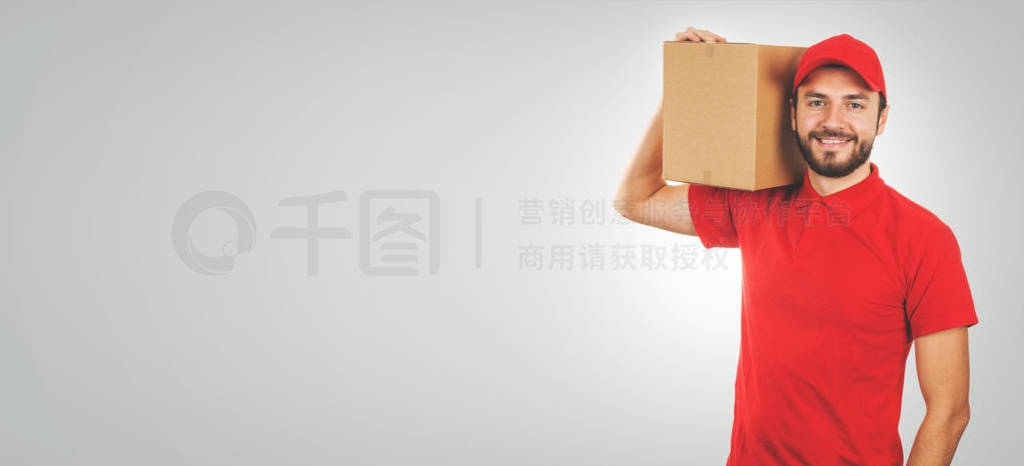 young smiling delivery man in red uniform and with shipment box