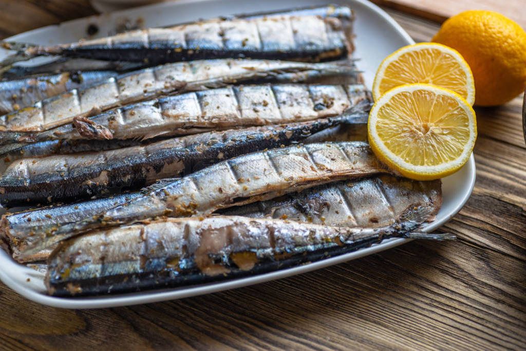 Smoked saury on a white dish in the form of fish with lemon and