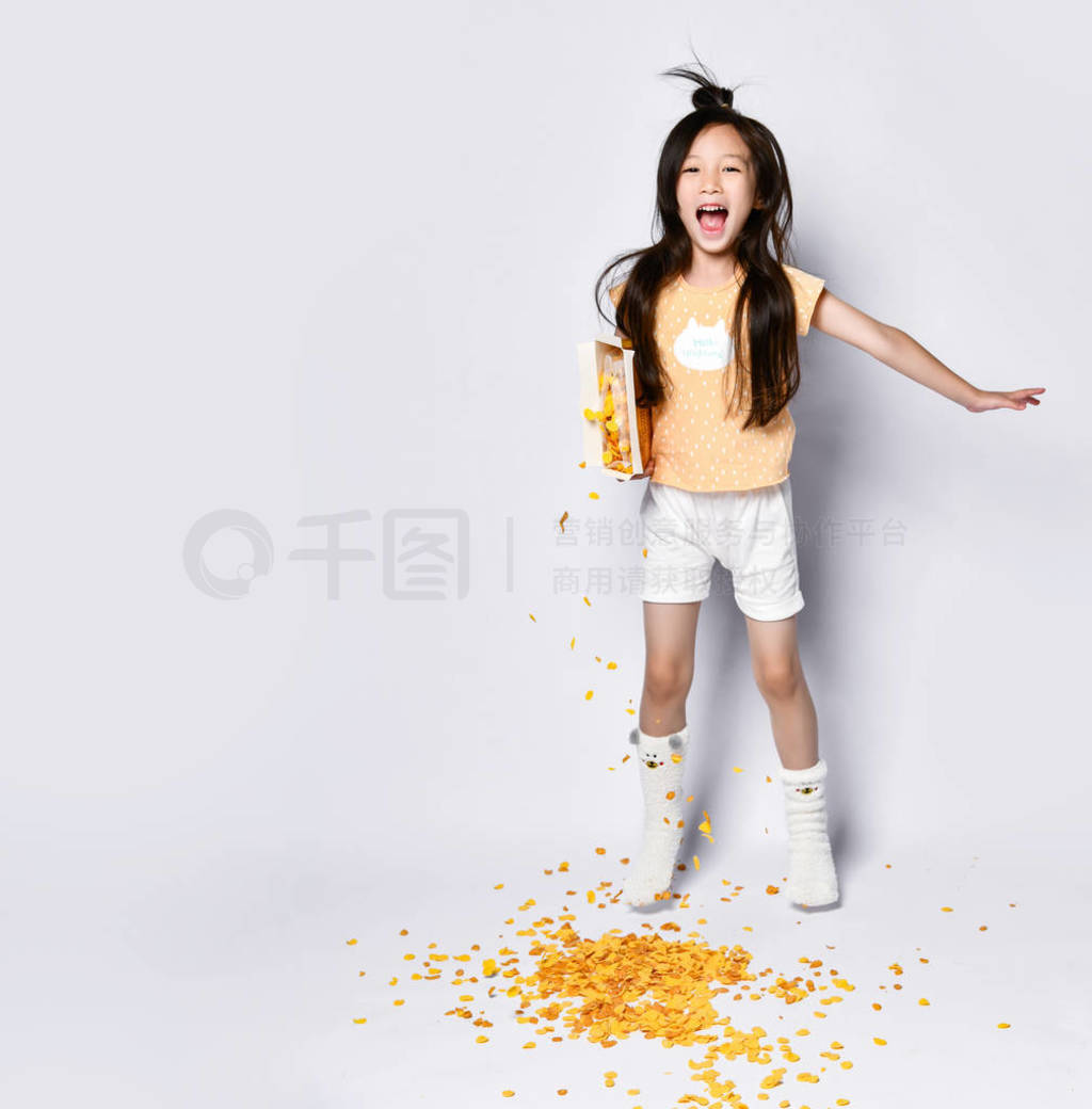 Joyful asian girl kid in home clothes laughs, jumps and does not