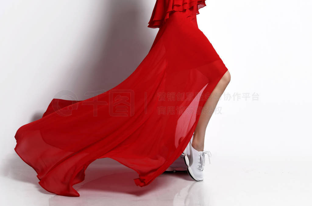 Sport woman legs in sneakers running in fashion red dress windy