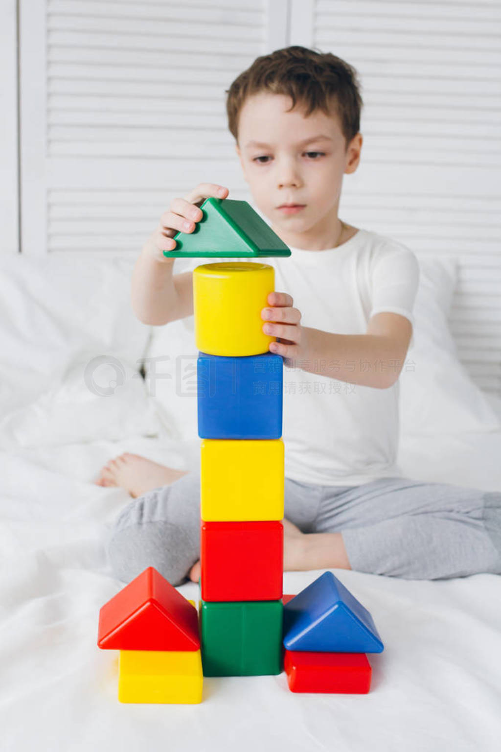 Boy plays and builds a tower of colorful plastic cubes