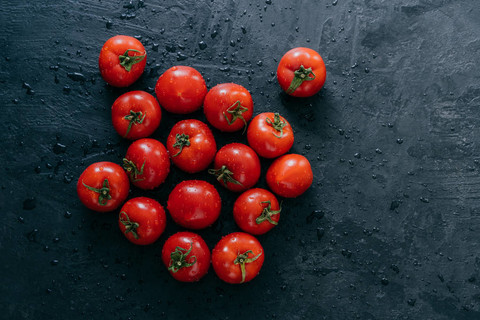 成熟的红色新鲜西红柿，黑色背景上有孤立的水滴。海尔鲁姆蔬菜。生食。健康营养。丰收