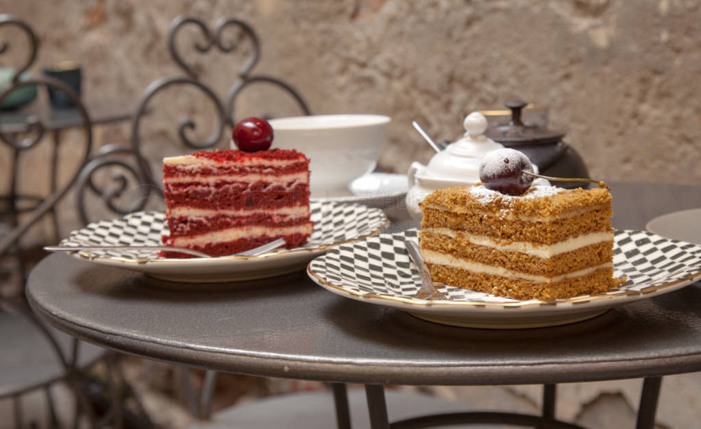 two pieces of different cakes set on a table in a patio cafe