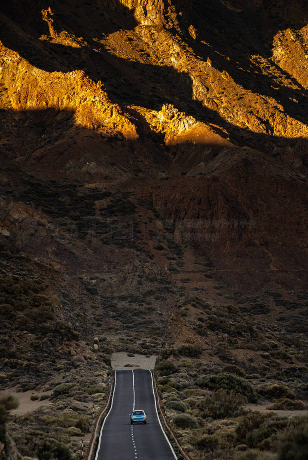 Long road in a mountain valley with a car on it