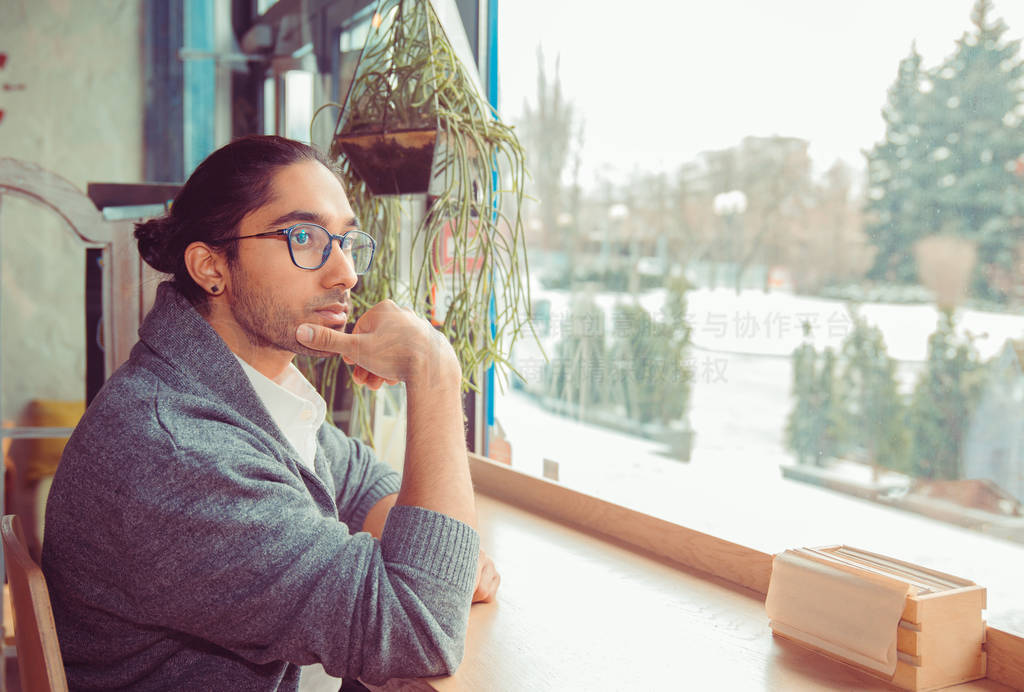 Man in living room looking through window, being thoughtful