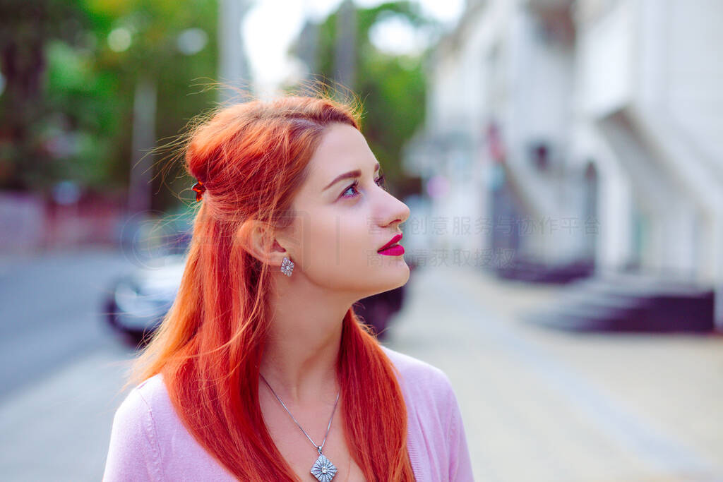 Thinking outside. Portrait of redhead woman outdoors near apartm