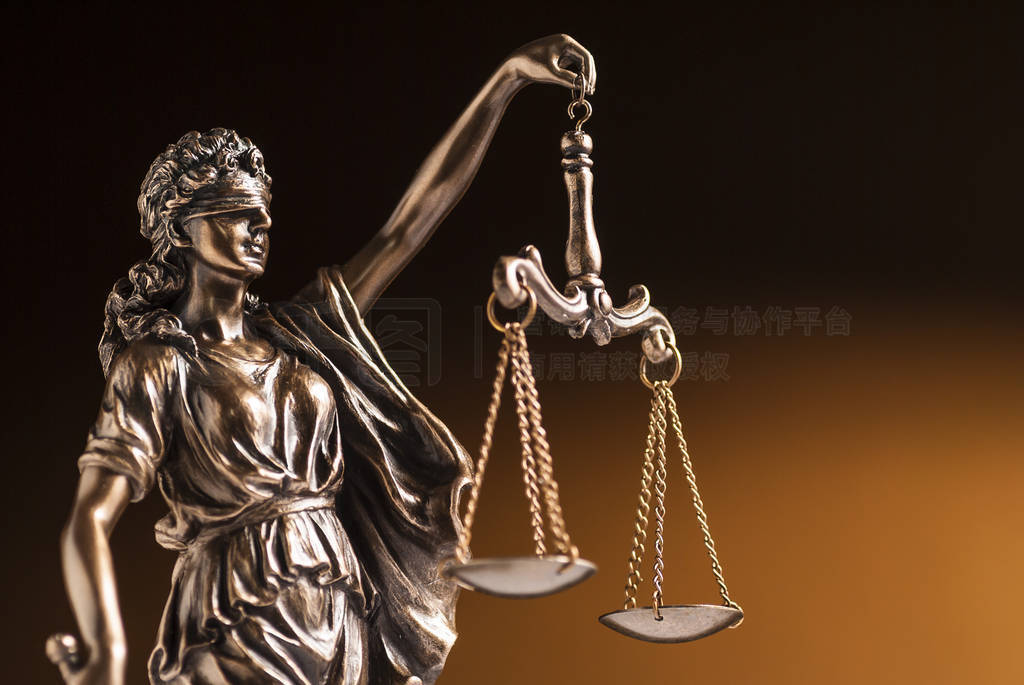 A blindfolded bronze statue of Justice on a brown background