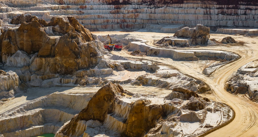 excavator loading dump truck with raw kaolin in kaolin open pit