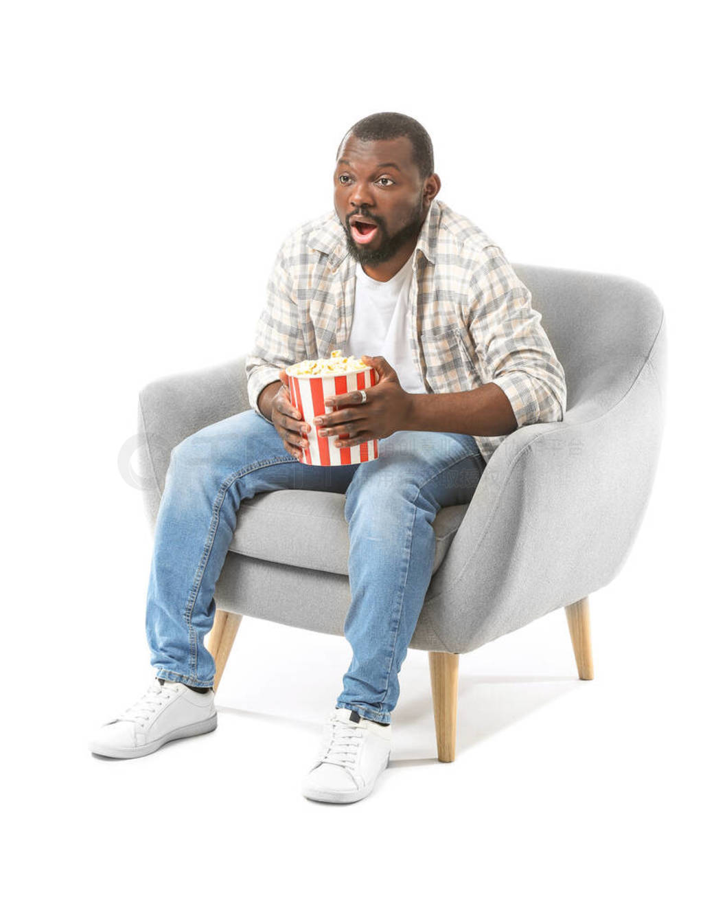 Emotional African-American man with popcorn watching TV while si